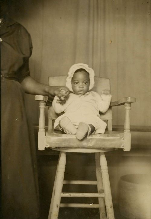 Unidentified infant sitting in highchair, undated. 